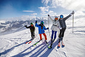 Family enjoy a skiing together in mountains on a sunny winter day