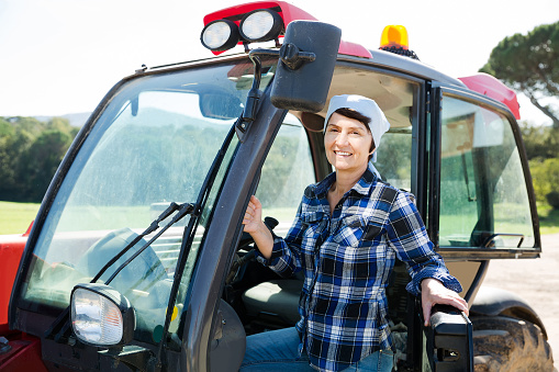 Confident positive american female farm owner driving tractor