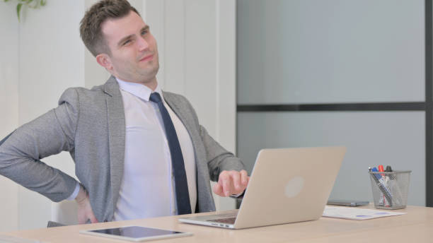istock Young Businessman with Back Pain Working on Laptop 1470557251
