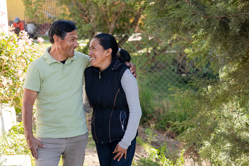 Portrait of hispanic couple hugging while smiling - Senior adult couple enjoying walk in the park - Latin retired adults