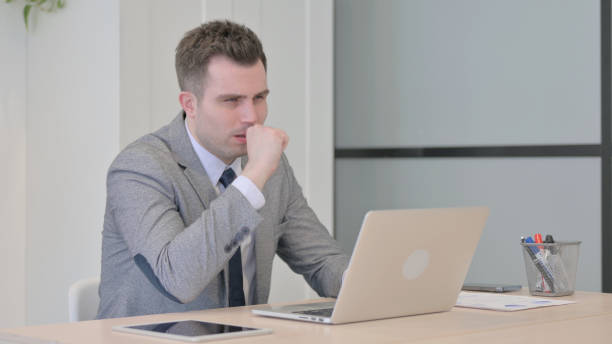 istock Young Businessman Coughing while Working on Laptop 1470562586