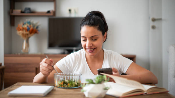 la hermosa mujer sonriente se alimenta sana y usando un teléfono - diabetes food fotografías e imágenes de stock