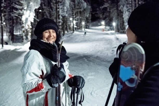 istock Two women talking on a lighted ski slope at night. 1470567716