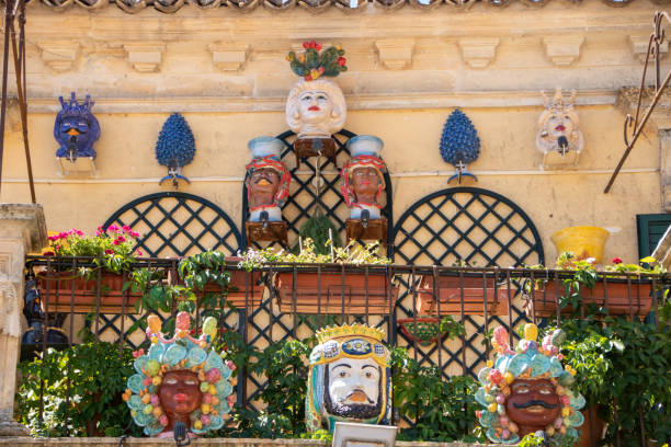 At Palazzolo Acreide, Italy , On 03 - 08 - 2022 - Traditional ceramic Moor heads and pine cones on a baroque balcony, Sicily, Italy