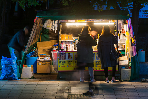 Women buying fast food from a street food stall in central Seoul, Korea.