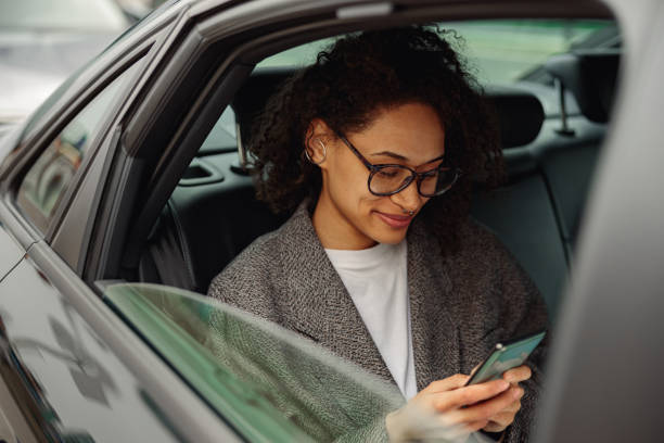 Pretty woman entrepreneur use phone during traveling to office in back seat of luxury car stock photo