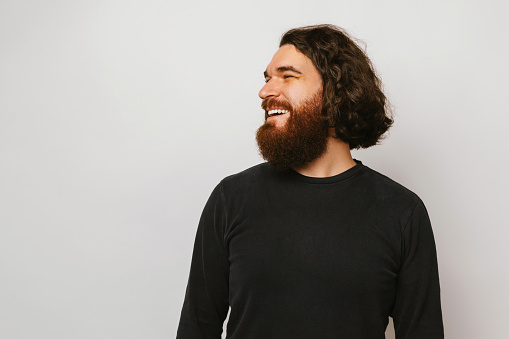 Side view portrait of a cool and handsome laughing bearded man with long brown hair.