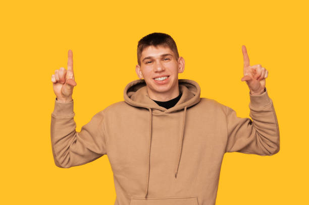 istock Cheerful young smiling man is pointing up above his head with both hands. 1470569762