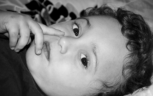 Boy lying on the bed in the bedroom of an old house far from the city center.