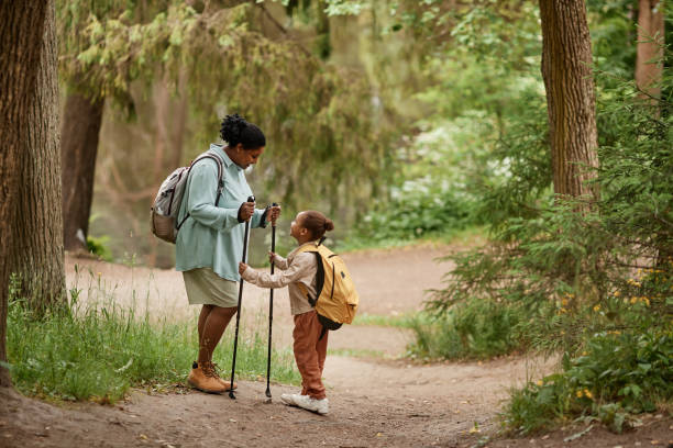 Side view black mother and daughter hiking together in beautiful forest trail