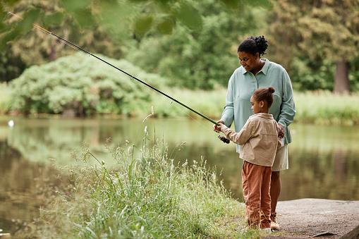 istock Side view caring black mother teaching little girl fishing 1470571505