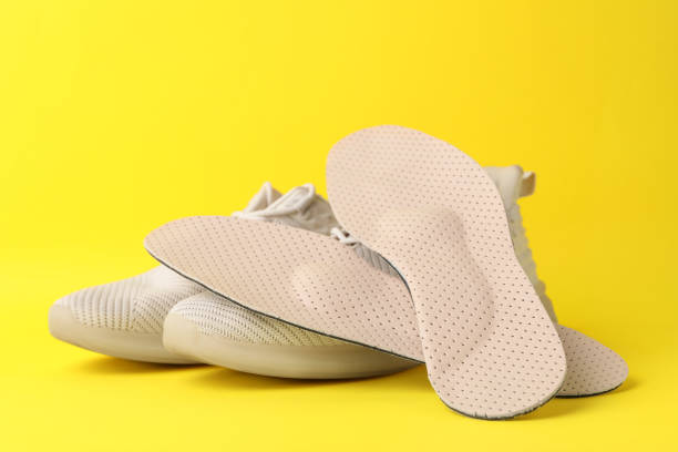 plantillas y zapatos ortopédicos beige sobre fondo amarillo - insoles orthotic human foot podiatry fotografías e imágenes de stock