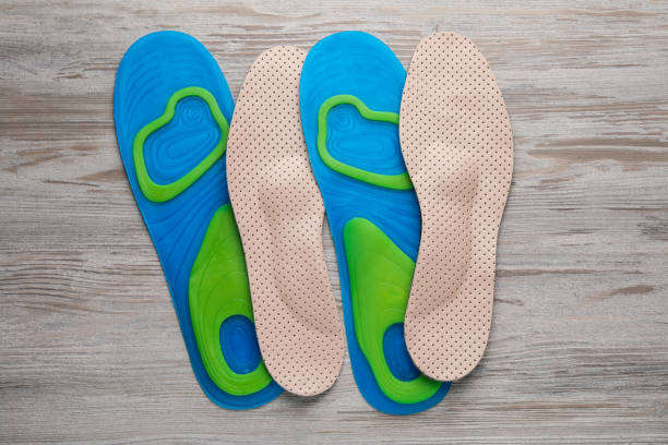 plantillas ortopédicas azules y beige sobre fondo de madera, planas - insoles orthotic human foot podiatry fotografías e imágenes de stock