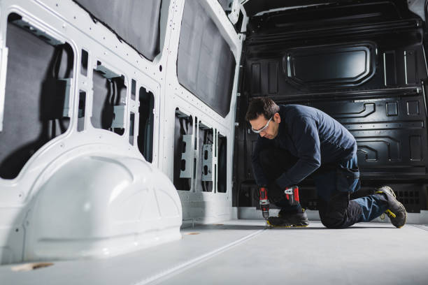 Converting a van into a home on wheels. Man working with a battery-powered drill inside a van. stock photo