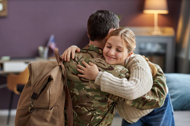 軍隊から帰宅する父親を抱きしめる笑顔の女の子 - family with one child family two parent family father ストックフォトと画像