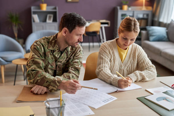 istock Front view father wearing military uniform helping daughter with homework 1470572599