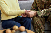 Close up of military man holding hands with wife
