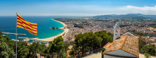 Coastline of Costa Brava near resort Blanes. Sea coast of Costa Brava region with panoramic view of the resort Blanes. Wide landscape with scenic of beaches on Mediterranean coast of Spain and flag of Catalonia, top view. barcelona province stock pictures, royalty-free photos & images