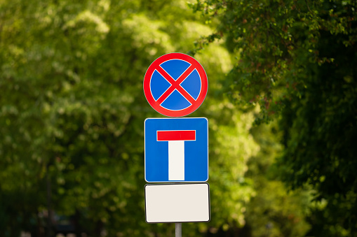 Post with different traffic signs near trees outdoors