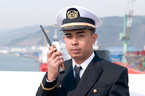 Navigation officer is talking by VHF radio, looking ahead on the navigation bridge of ocean ship