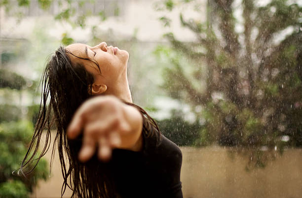 Worship in the rain A woman praying and/or in worship while standing under the rain.(Or this could just be a woman enjoying the rain) drenched stock pictures, royalty-free photos & images