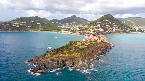 A view over St. Kitts Island with residential area and beaces on the foreground and lush green hills on the background.