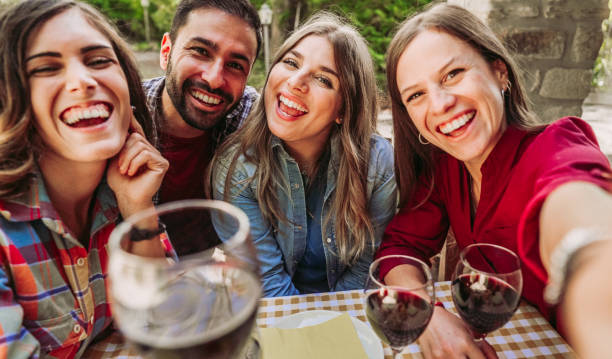 Happy friends having fun drinking red wine out side at farm house bar - Young people sharing harvest time together at countryside homestead stock photo