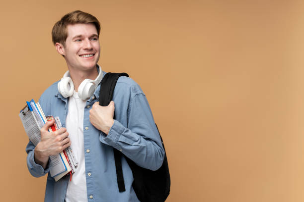 istock Smiling young college student with books and backpack looking away 1470582528