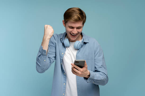 istock Happy satisfied man holding smartphone and smiling making yes gesture 1470582739