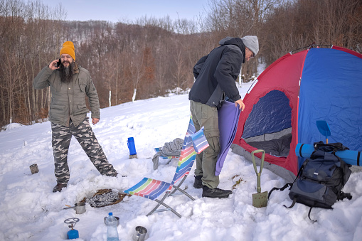 Winter camping on mountain while having a call on mobile phone
