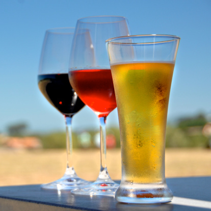three glasses - one with beer and two with wine on outside table, summer day
