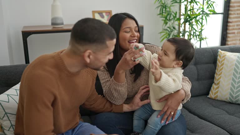 Couple and son sitting on sofa playing at home