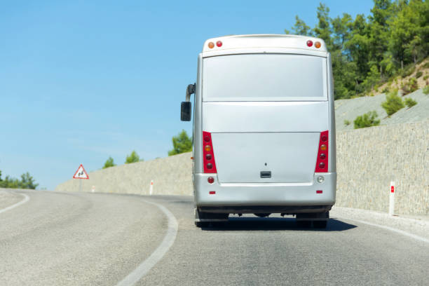 istock Big tourist bus rides along a mountain road with a protective wall. 1470587104