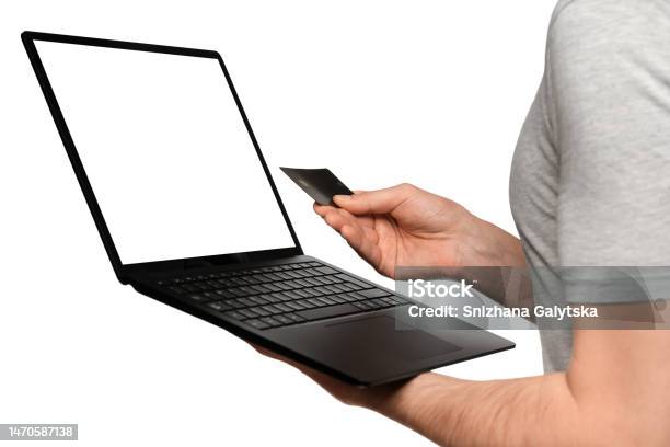 A Man In A Tshirt Holds A Laptop An Ultrabook And A Bank Card With His Second Hand Makes An Online Purchase Stock Photo - Download Image Now