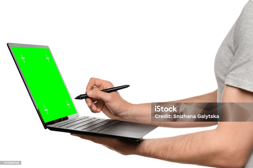A man in a T-shirt holds a laptop, an ultrabook, and puts an electronic signature with his other hand. Adult Stock Photo