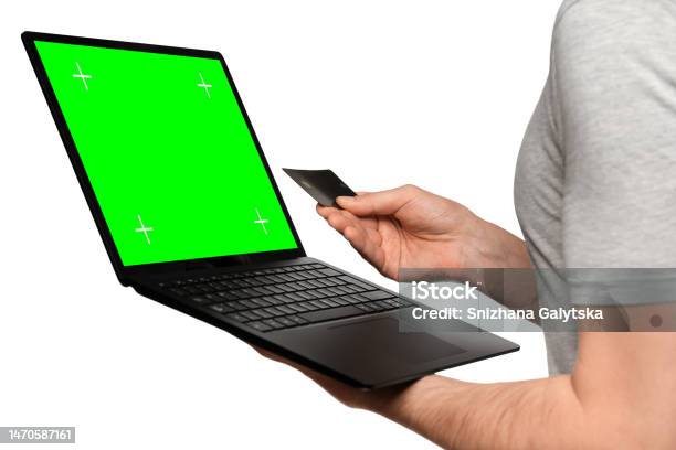 A Man In A Tshirt Holds A Laptop An Ultrabook And A Bank Card With His Second Hand Makes An Online Purchase Stock Photo - Download Image Now