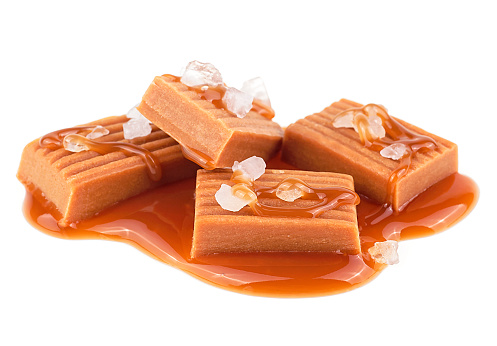 Toffee candies with caramel sauce and sea salt isolated on a white background. Golden Butterscotch toffee caramels.