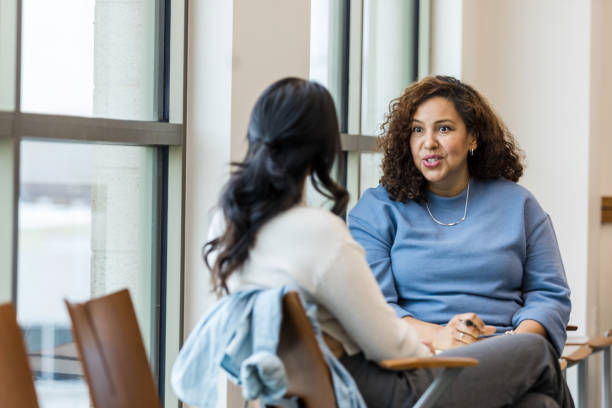 Supervisor meets with mid adult female employee to mentor her regarding a new position she is interested in stock photo