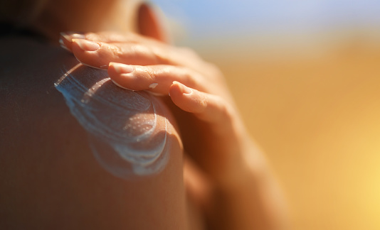 Mujer aplicando crema bloqueador solar en su hombro. photo