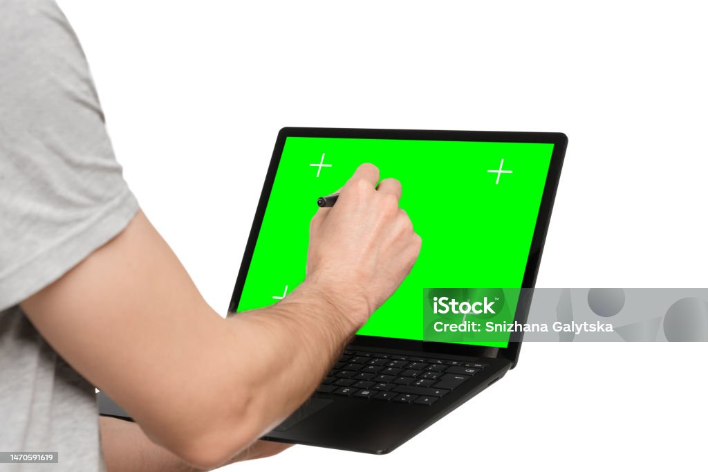 A man in a T-shirt holds a laptop, an ultrabook, and puts an electronic signature with his other hand. Adult Stock Photo