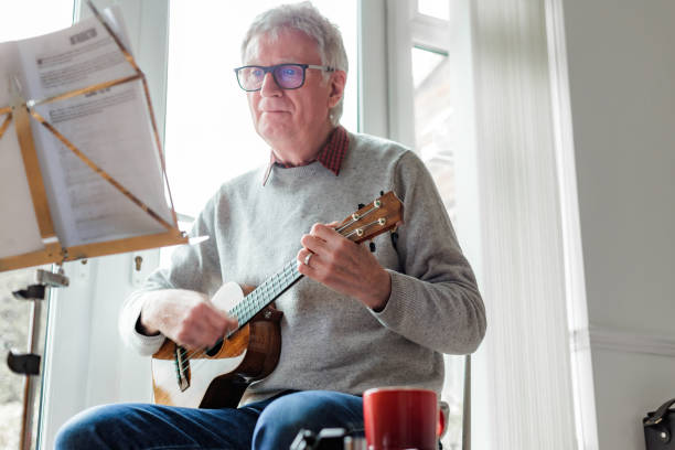 istock Happy senior man playing ukulele at home 1470593205