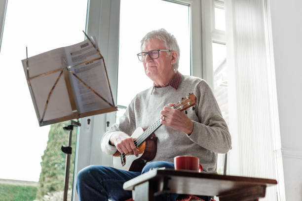 istock Happy senior man playing ukulele at home 1470593211