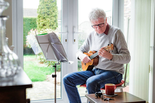 istock Happy senior man playing ukulele at home 1470593217