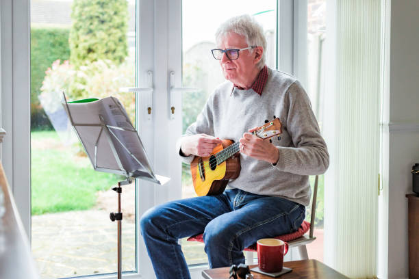 istock Happy senior man playing ukulele at home 1470593219