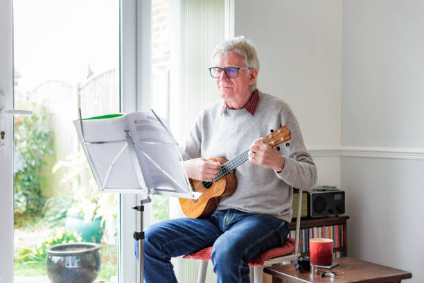 istock Happy senior man playing ukulele at home 1470593252