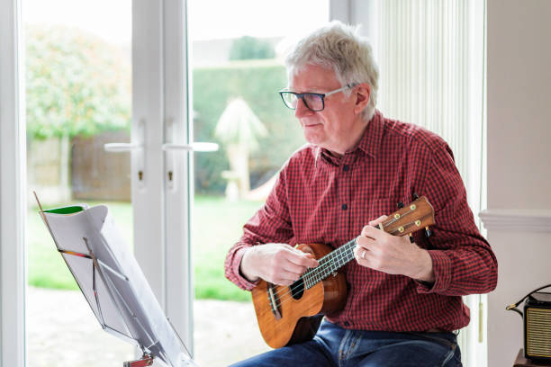 Happy senior man playing ukulele at home
