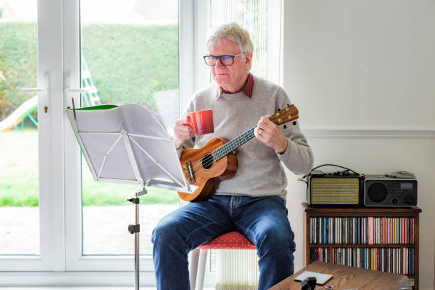 istock Happy senior man playing ukulele at home 1470593268