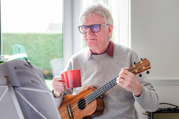 istock Happy senior man playing ukulele at home 1470593296