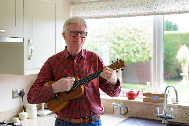 istock Happy senior man playing ukulele at home 1470593298