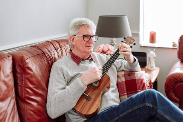 istock Happy senior man playing ukulele at home 1470593360